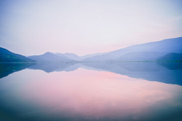 Fototapeta na wymiar Serene Horizon: Minimal Landscape of Lake and Mountain under Pastel Pink Dusk Sky