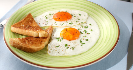 fried eggs with toast on a green plate. close-up. angle view. camera tracking. white background. traditional breakfast. sunny day.