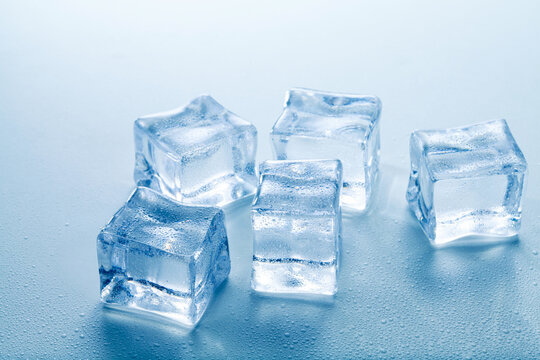 clear ice cubes with water drops on blue background.