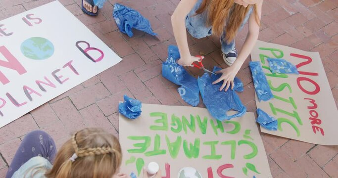 Video of diverse schoolchildren making protest placards in schoolyard, copy space