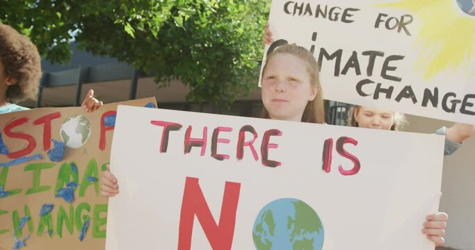 Video of diverse schoolchildren holding protest placards and chanting outdoors, copy space