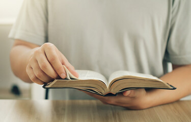 Close-up of Christian man's hands while reading the Bible outside.Sunday readings, Bible education. spirituality and religion concept. Reading a book.