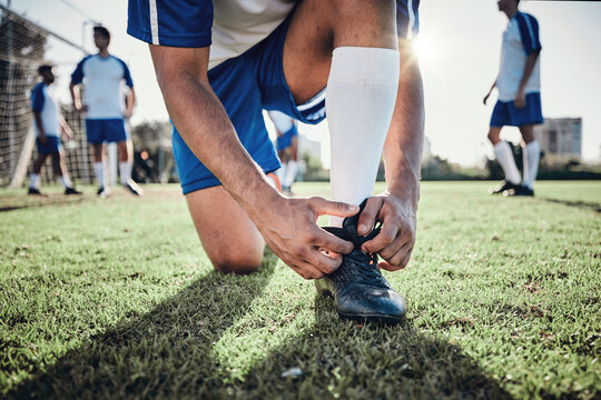 Hands, man and tie shoes on soccer field, prepare for training or fitness games. Closeup, football player or athlete getting ready with sneakers lace in sports, competition and contest on grass pitch