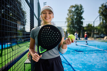 Young athletic woman playing paddle tennis on outdoor court and looking at camera.