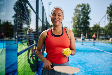 Happy black athlete playing pickleball with her friends and looking at camera.