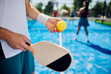 Close up of man serving ball while playing mixed doubles in pickleball.