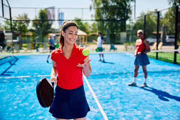 Happy female paddle tennis player during mixed doubles match on outdoor court.