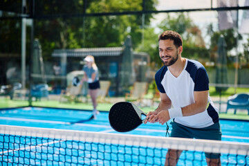 Happy athlete during paddle tennis mixed doubles outdoor court.