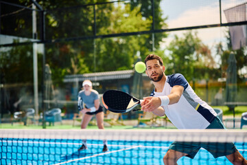 Young athletic man plays padel on outdoor tennis court.