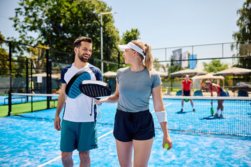 Happy sports couple talk while playing mixed doubles in paddle tennis. - obrazy, fototapety, plakaty
