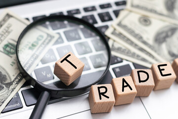 On the laptop, on wooden cubes near the pen, the word TRADE is written.