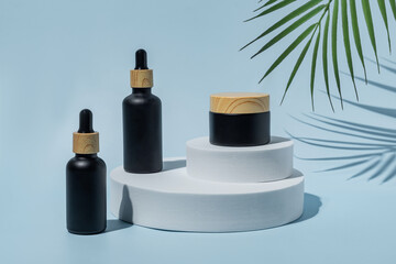 Trendy background with natural cosmetic skincare bottles. Product presentation. Beauty and body care product concept. Beauty oil and face cream in black frosted glass bottles.