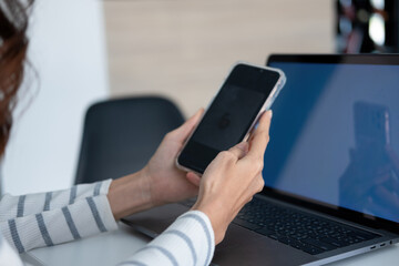 Young woman engaged in online study or project work with smartphone.