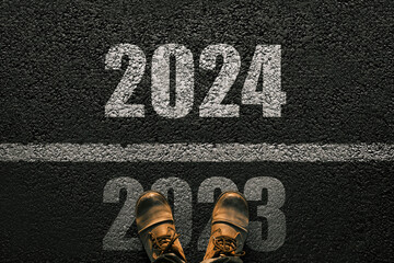Man walks on asphalt and crosses the line by 2024. New year 2024. Men's legs with leather shoes go...