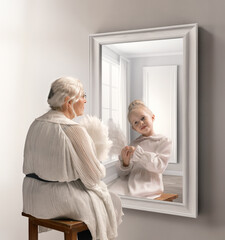 Creative conceptual collage. Senior lady, woman looking in mirror with reflection of little girl,...