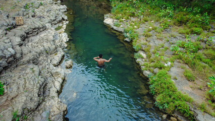 young man alone swimming in a clean and beautiful river