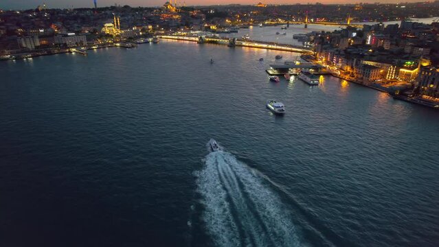 Aerial drone view of Istanbul at sunset, Turkey. Multiple residential buildings, mosques, Galata and Metro bridges over the Golden Horn waterway with multiple floating ships, nightlights