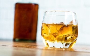 Whiskey with ice in glass and bottle of whiskey on white backgrounds