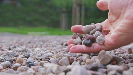 Caucasian Male Grabbing Small Pebble Rocks from Ground With Bare Hand