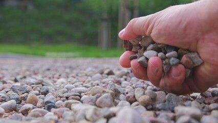 Caucasian Male Grabbing Small Pebble Rocks from Ground With Bare Hand