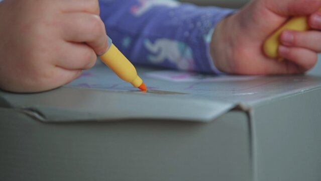 Creative Caucasian Preschooler Toddler Child Colouring Cardboard Box using Felt Tip Pen Permanent Marker