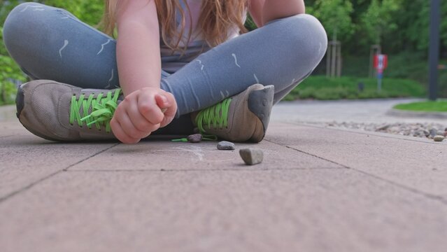 Caucasian Girl Mastering Dexterity Game of Jackstones Scatter Jacks Knucklebones using Small Rocks