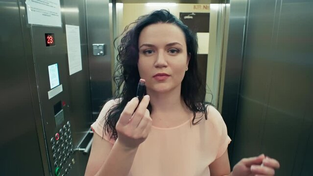 The girl rushes to the party and puckers her lips in the elevator. A woman enters the elevator. High quality 4k footage