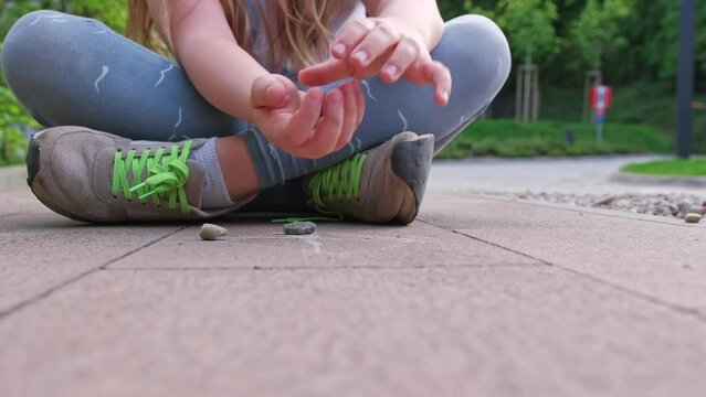 Caucasian Girl Mastering Dexterity Game of Jackstones Scatter Jacks Knucklebones using Small Rocks