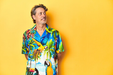 Cheerful middle-aged man in Hawaiian shirt emanating summer vibes on a yellow background