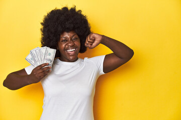 African-American woman holding cash, displaying wealth feels proud and self confident, example to...
