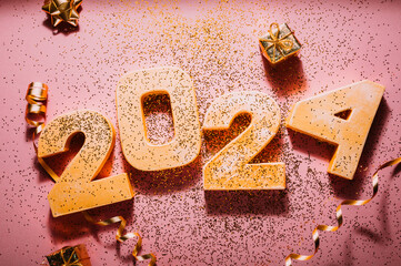 Happy New Year 2024. Golden digits 2024 with glitter and xmas decorations nearby. Holiday Party Decoration or postcard concept with top view and copy space.
