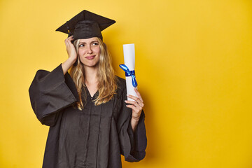 Young caucasian woman wearing a graduation robe holding a diploma Ybeing shocked, she has...