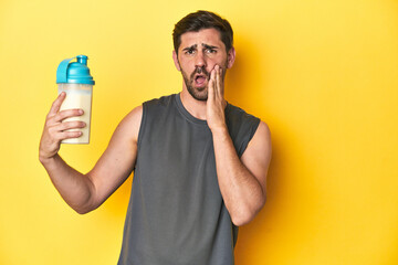 Fit man with protein shake, yellow studio background is saying a secret hot braking news and...