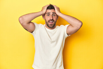 Fototapeta na wymiar Caucasian man in white t-shirt on yellow studio background screaming, very excited, passionate, satisfied with something.