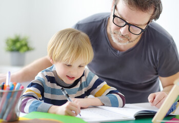 Father helping child do his homework at home. Tutor teaching boy with ADHD. Education for kids.