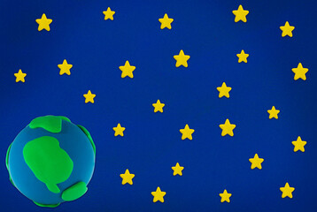 plasticine yellow star and blue green earth on blue background