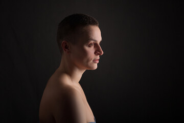 portrait of young woman with short hair and bare shoulder on black background
