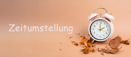 Alarm clock with autumn foliage, end of daylight saving time in fall, winter time changeover stands...