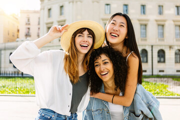 Happy multiracial young group of female friends having fun on summer vacation. Three diverse millennial women enjoying weekend getaway in the city. Friendship and youth concept.