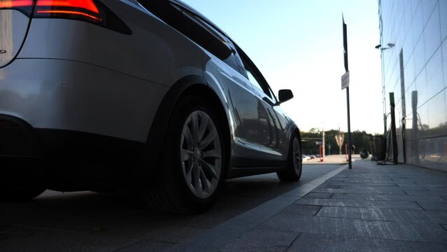 Driver coming to car and opens door for businesswoman. Chauffeur uncover door of automobile for female passenger. Elegant business woman get out from auto and walking to office building. Slow motion