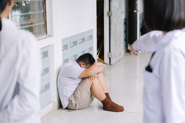 Thai student bullying victim by classmates crying sadly being bullied, concept of being bullied by schoolmates causing stress and physical and psychological harm.