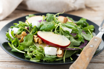 Autumn salad with apples and walnuts on wooden table