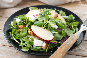 Autumn salad with apples and walnuts on wooden table