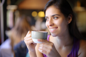 Happy woman holding coffee mug looks at side