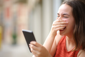 Happy woman laughing loud checking cell phone