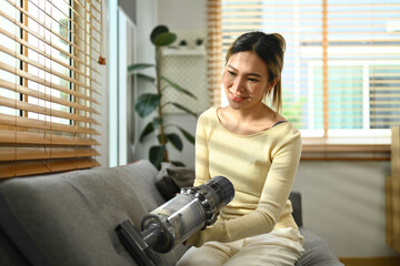 House cleaning , housework concept. Millennial asian woman vacuuming and cleaning the dust on couch on living room © Prathankarnpap