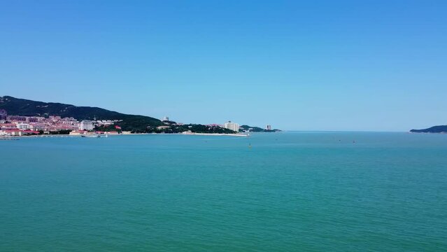 Aerial panorama shot of the beautiful blue sea off the coast of weihai city, china at xingfu park with a view of the city buildings in asian architecture on a sunny summer day