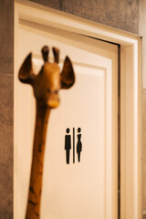 Une girafe devant un panneau indiquant les toilettes