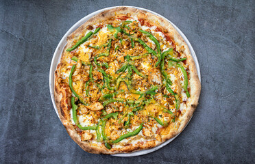Delicious chicken pizza with cheddar and green peppers on rustic table. top view.