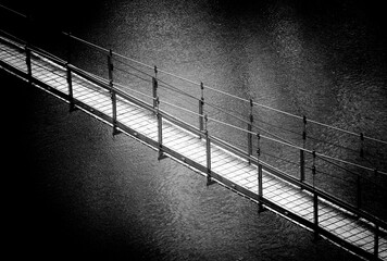 so-called Tibetan bridge suspended over a river, black and white photo
